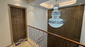 Un intérieur moderne avec une porte en bois, une rambarde en métal et un grand lustre en cristal.