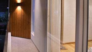 Un bâtiment moderne avec une façade en bois, une porte en verre donnant sur un espace intérieur et un cadre de porte visible.