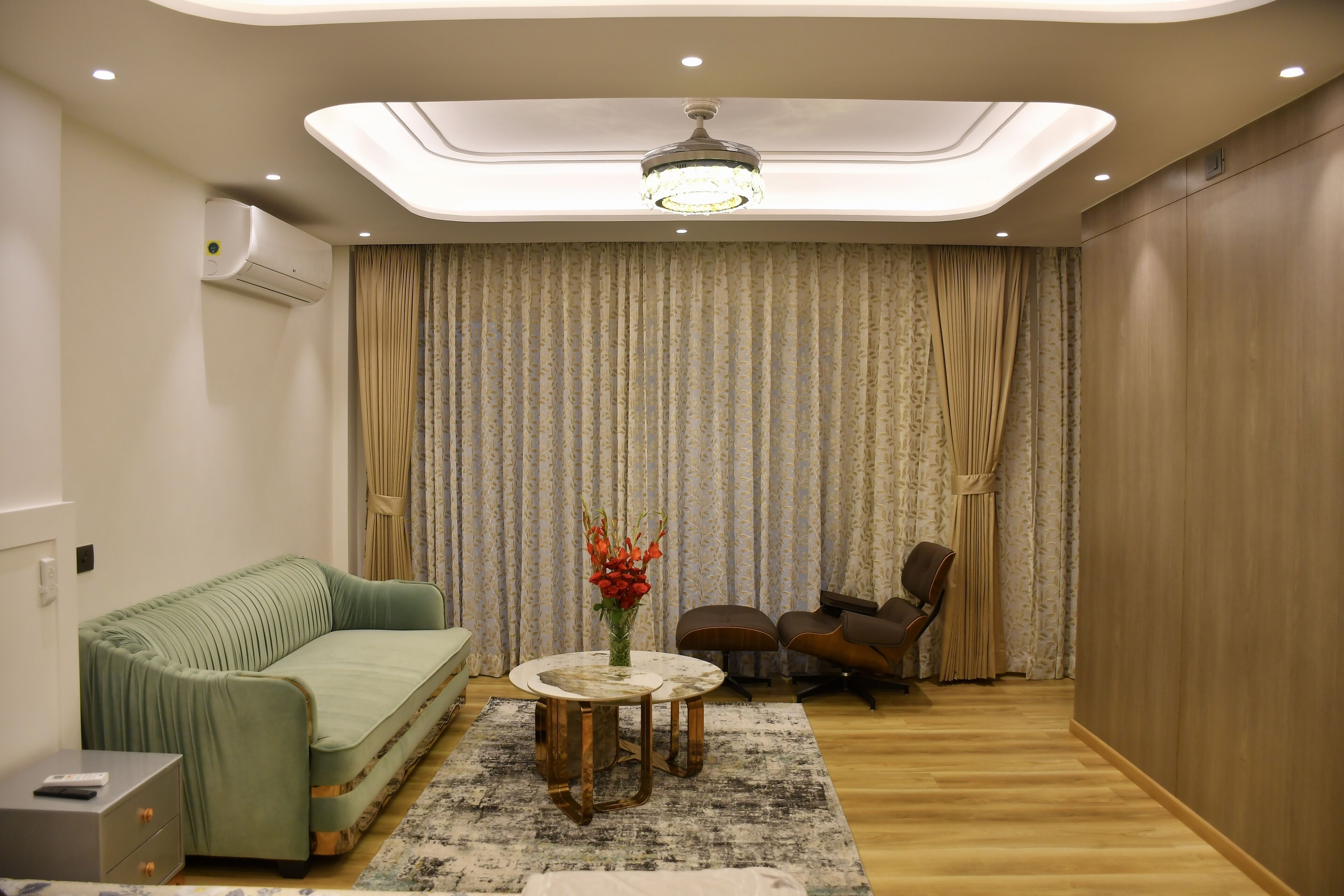 A modern living room with a sofa, chairs, a round table, and a decorative vase.