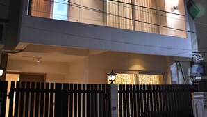 Un immeuble à deux étages doté de balcons, d’une entrée sécurisée par un portail et d’une enseigne bien visible.