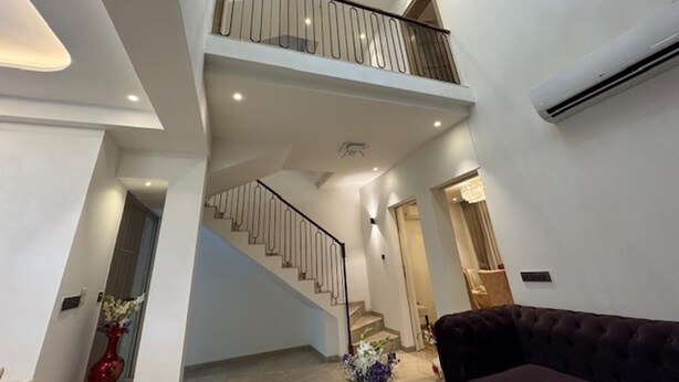 Un intérieur spacieux avec un escalier menant à un balcon, un canapé confortable et un vase rempli de fleurs.