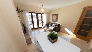 A spacious living area with a dining table, a sofa, and a large window providing natural light. - MAR DE VICEDO - PENTHOUSE 2 BEDROOMS WITH TERRACE (O Vicedo)