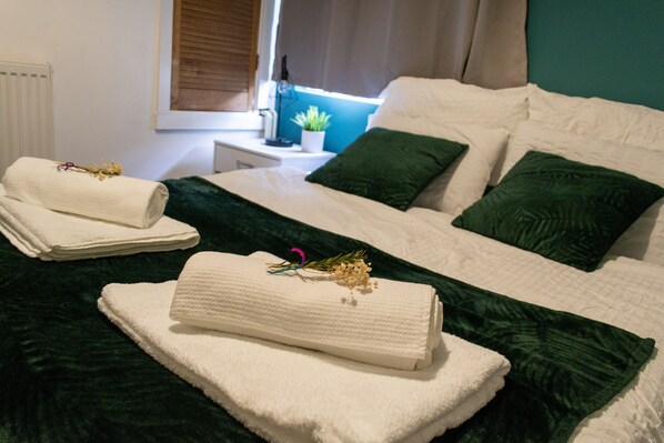 Relax in a serene space with a comfortable bed, green accents, and a potted plant.