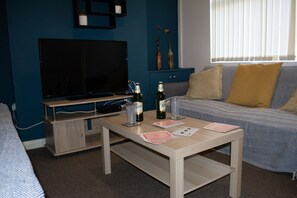 Relax in this cozy living space with a flat-screen TV, comfortable sofa, and a coffee table for unwinding.