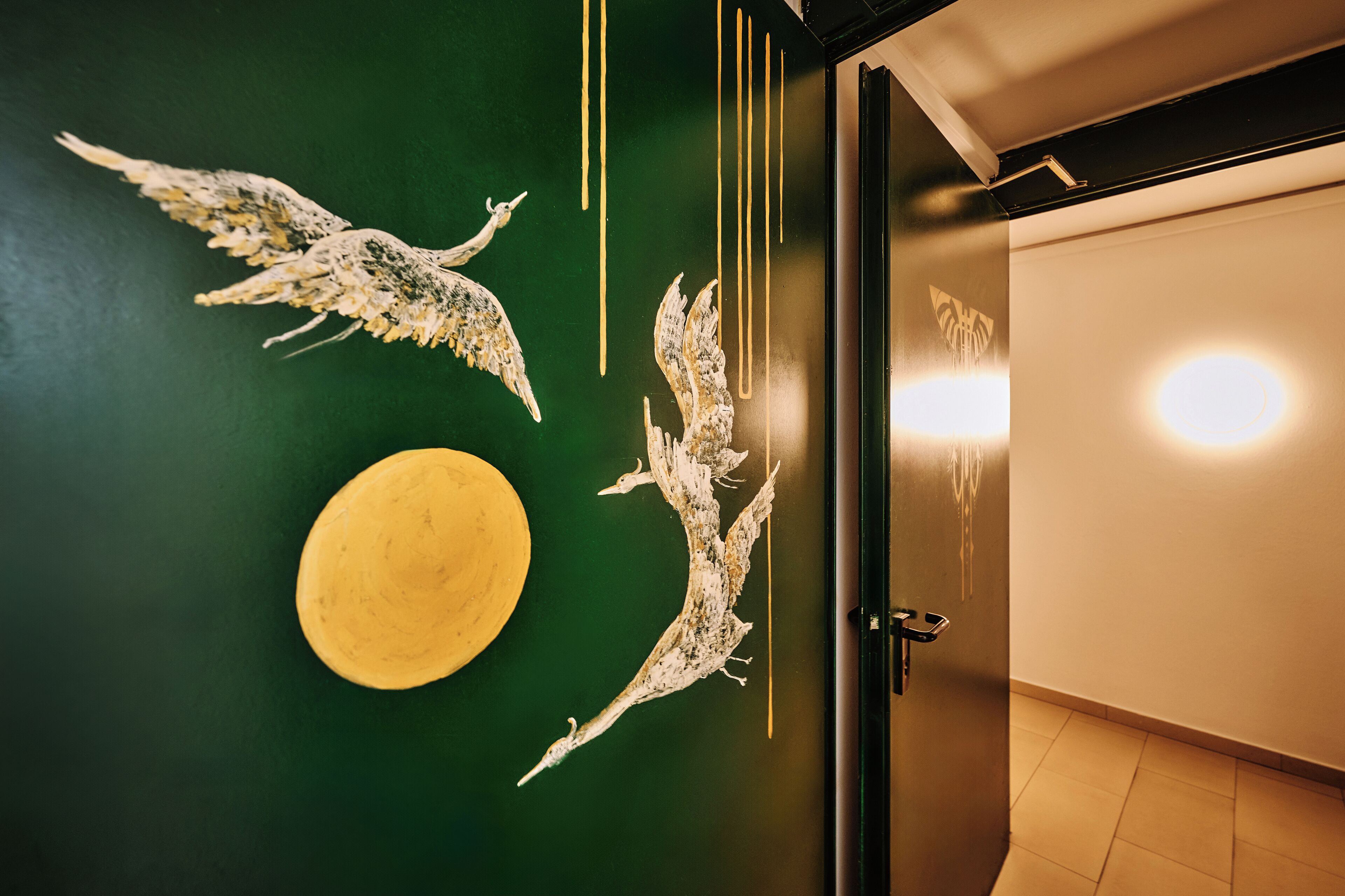 A room with a green wall, a yellow circular object, and two white bird sculptures.
