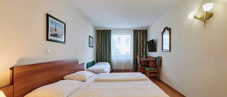 Una habitación de hotel con una cama grande, un escritorio, una silla, un televisor y una ventana con cortinas.