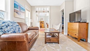 A living room with a brown leather sofa, a wooden coffee table, and a television on a wooden cabinet.