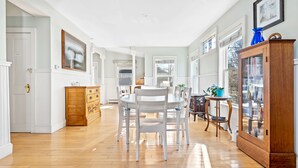 A spacious dining area with a round table and white chairs, a wooden cabinet, and a glass display case.
