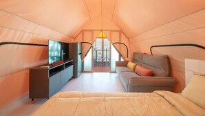 A cozy, well-lit tent-style room with a bed, a sofa, a TV, and a dining area with a table and chairs. - Gapyeong Haemogglamping (Gapyeong)