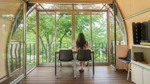 A tented room with a table and chairs, large windows, and a view of trees. - Gapyeong Haemogglamping (Gapyeong)
