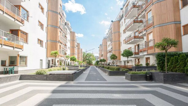 Un moderno complejo de apartamentos con un área peatonal central, balcones y pequeños árboles.