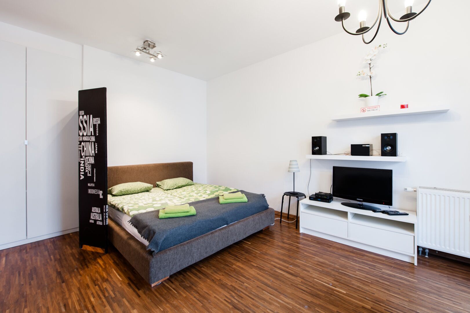 Une chambre moderne équipée d’un lit, d’un téléviseur, d’enceintes et d’un radiateur.