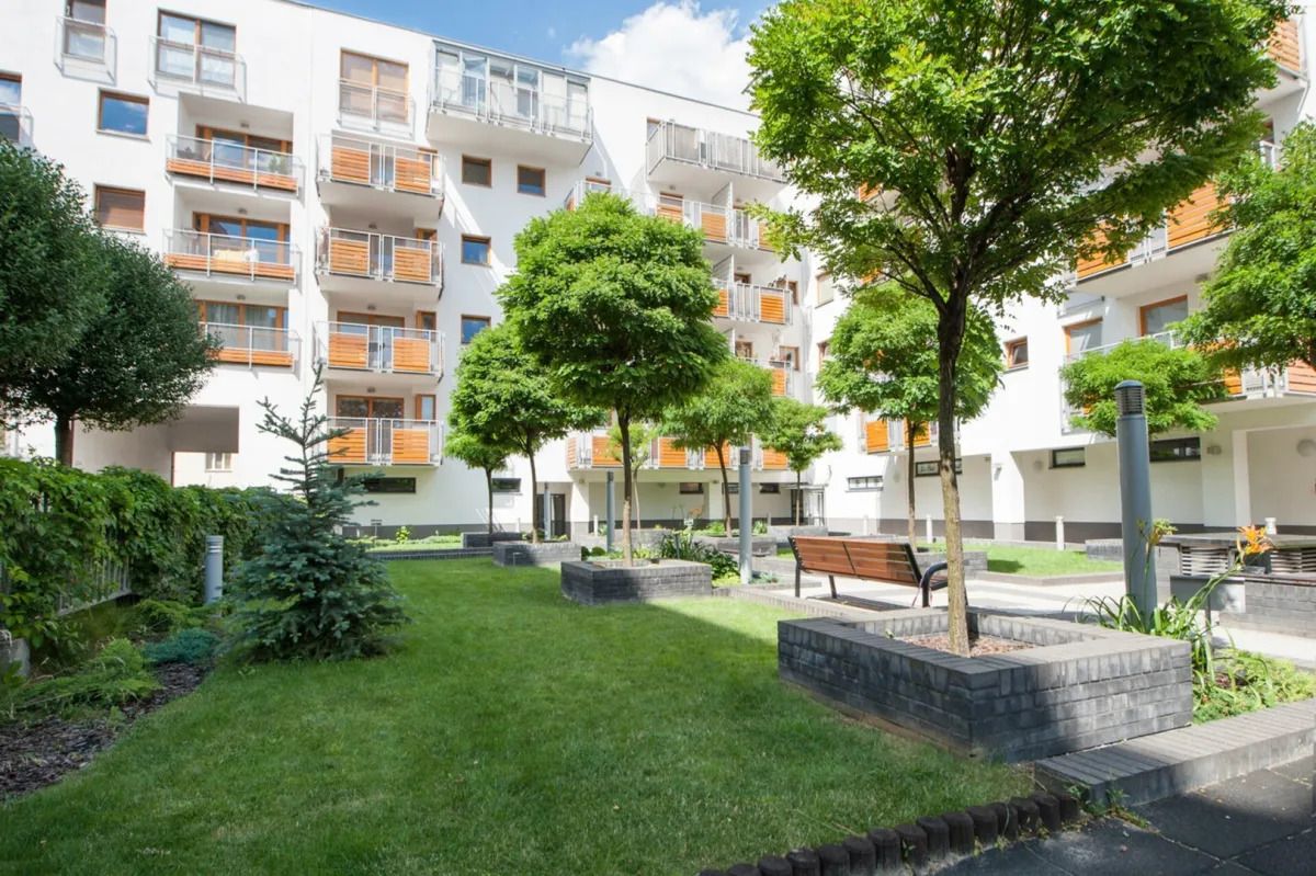 Un edificio residencial con varios balcones, césped cuidado y árboles.