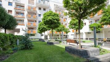 Un edificio residencial con varios balcones, césped cuidado y árboles.