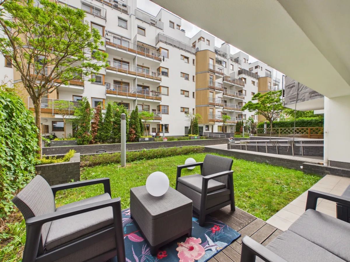 Un espacio exterior moderno con asientos y vistas a un edificio residencial de varios pisos.