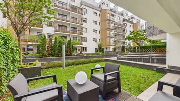 Un espacio exterior moderno con asientos y vistas a un edificio residencial de varios pisos.