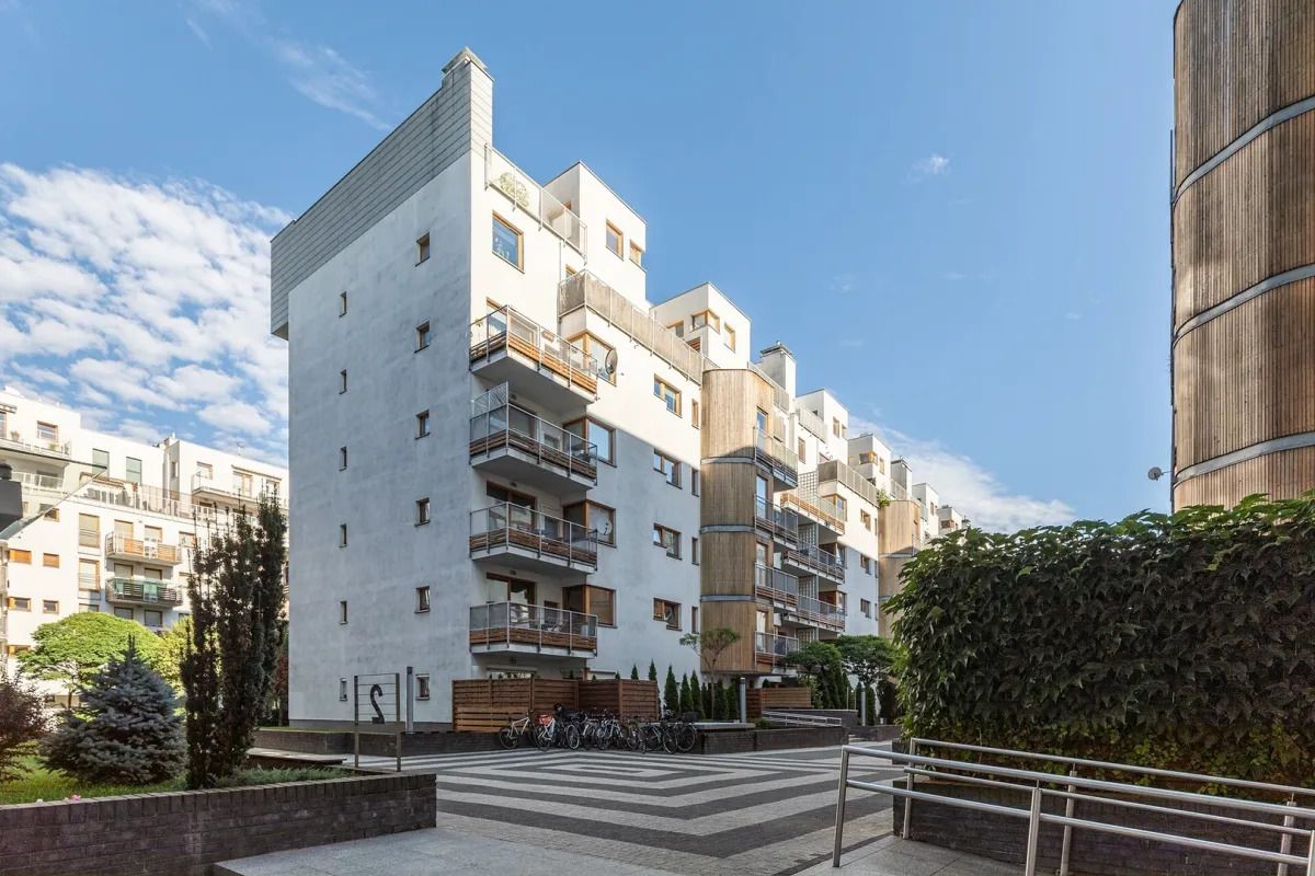 A modern apartment building with balconies, a courtyard, and a wooden structure.