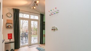 Un passadís amb terra de fusta, una prestatgeria de metall negre, un detector de fum, un rellotge i una finestra amb cortines.