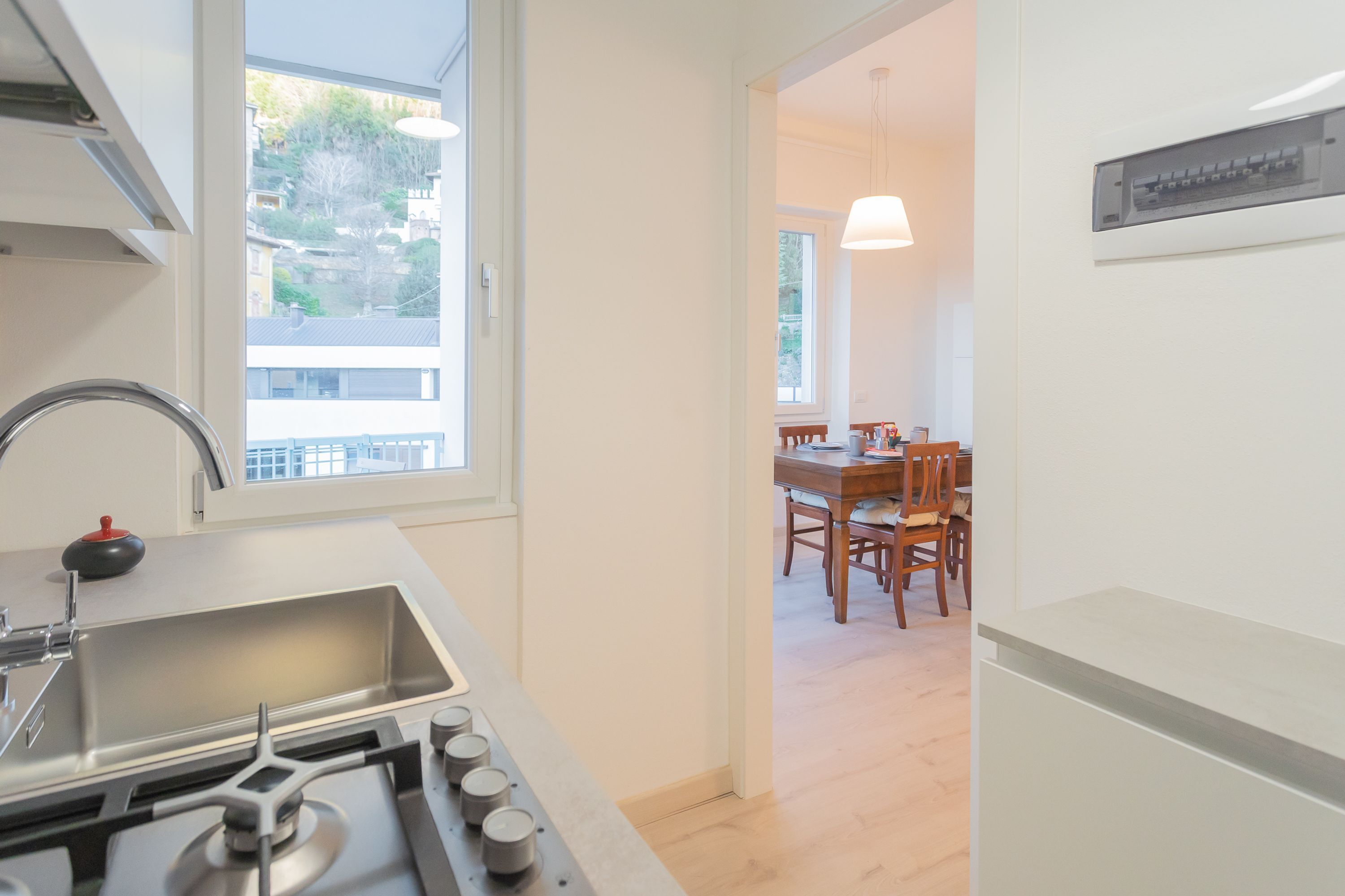 A modern kitchen with a stainless steel sink, a gas stove, and a window overlooking a residential area.