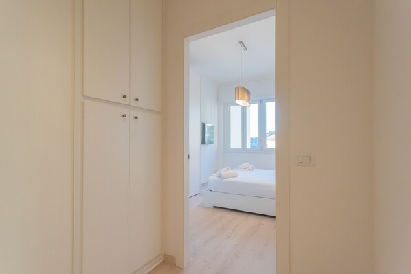 A bedroom with a bed, a wardrobe, and a hanging light fixture.