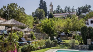 Une villa avec piscine, des chaises longues et un jardin.