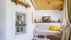 Une pièce chaleureuse avec un canapé blanc, des coussins jaunes et un plafond en bois.