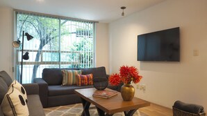 A modern living room with a sofa, a coffee table, and a flat-screen TV mounted on the wall. - Comfort Reforma By The Local Way (Mexico City)