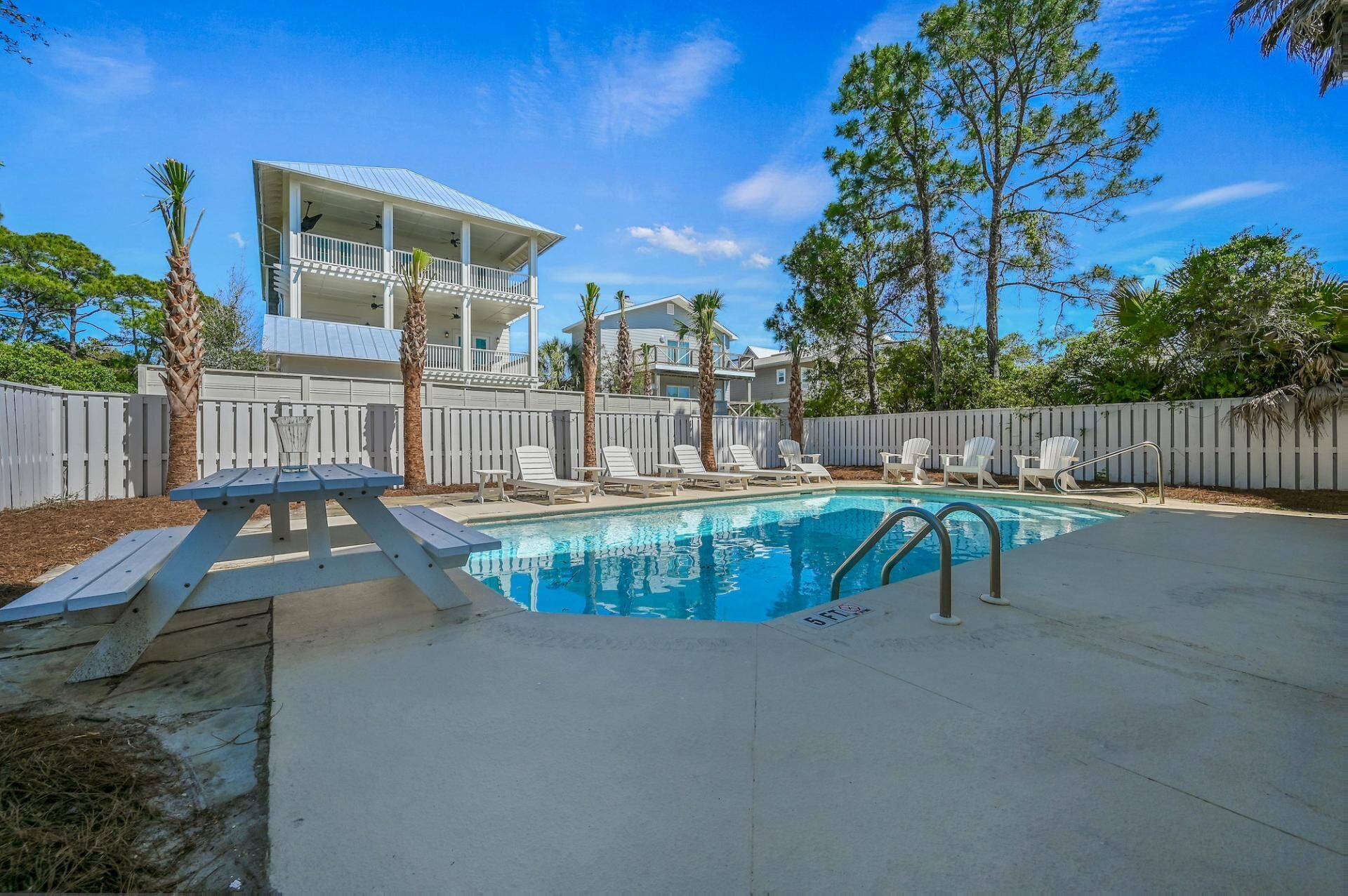 A swimming pool with lounge chairs and a picnic table.