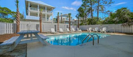 A swimming pool with lounge chairs and a picnic table.