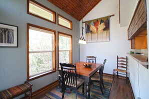 Un coin repas avec une table en bois, quatre chaises, un banc et un tableau accroché au mur.