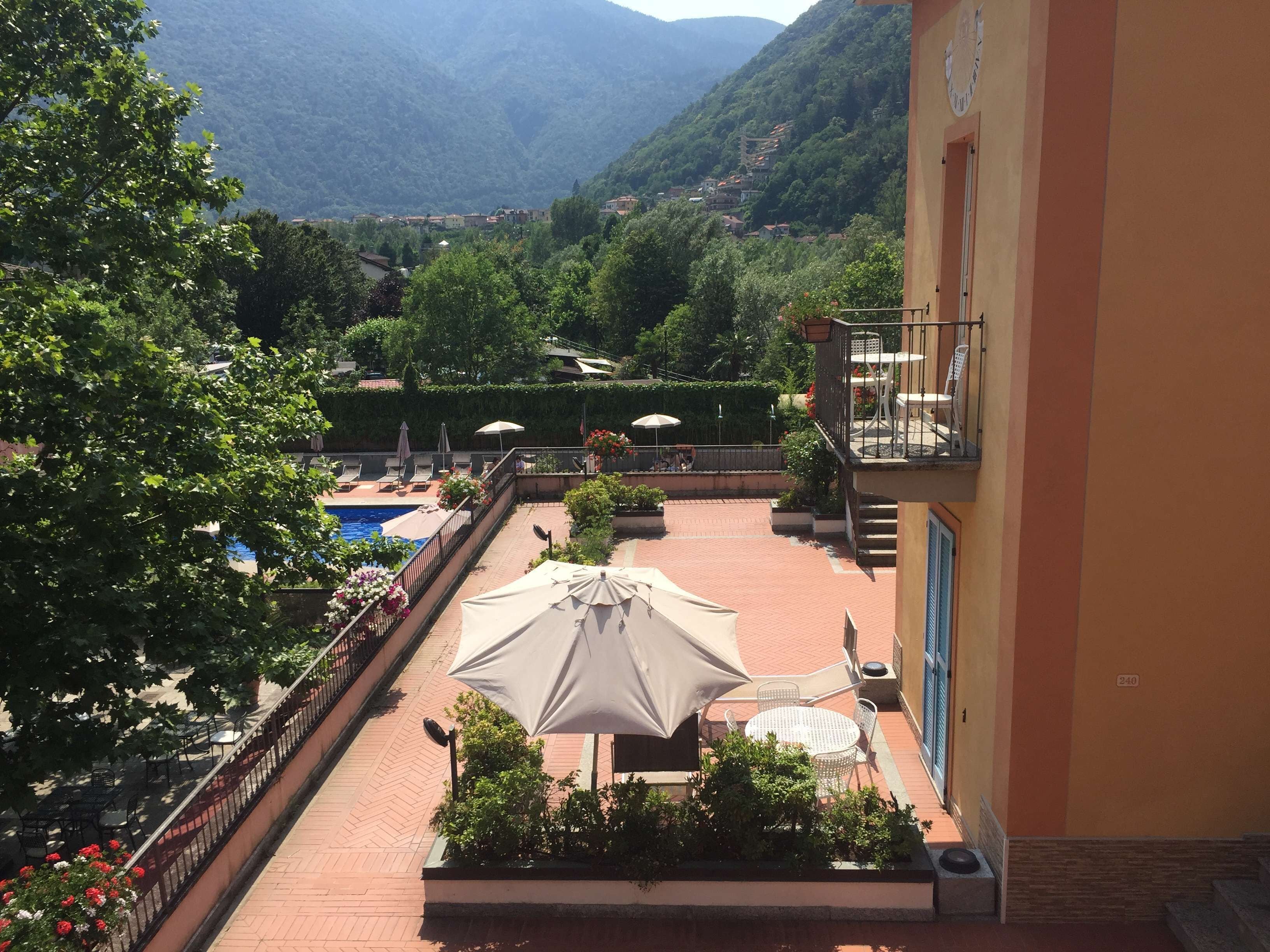 Ein Hotelbalkon mit Pool, Sitzgelegenheiten im Freien und Blick auf die Berge.