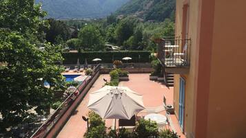 Ein Hotelbalkon mit Pool, Sitzgelegenheiten im Freien und Blick auf die Berge.