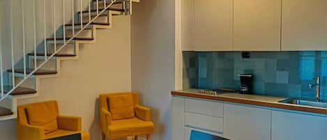 A modern kitchen with white cabinets, a built-in oven, and a coffee maker on the counter.