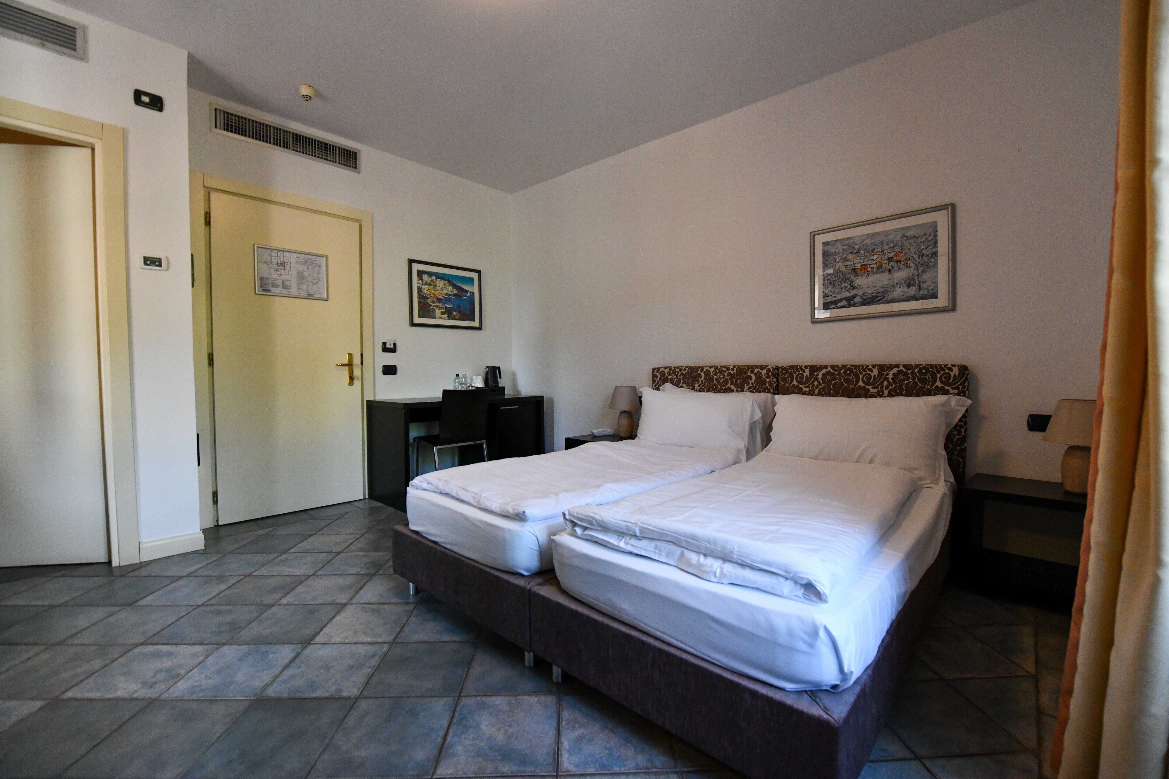 A hotel room with two beds, a desk, and a chair.