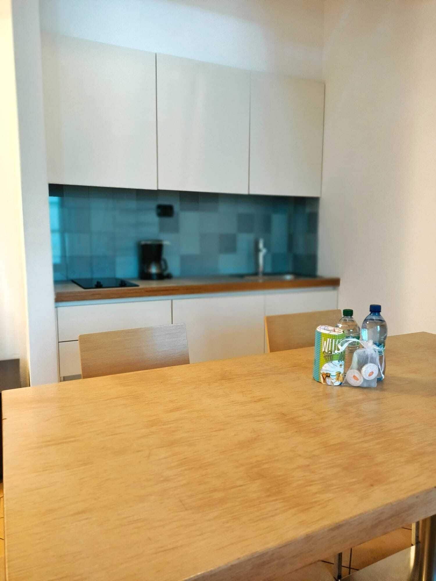 A small kitchen with a blue backsplash, a coffee maker, and a water dispenser on the counter.