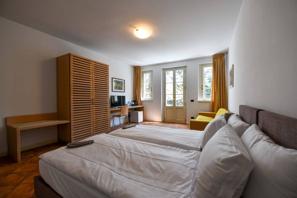 Een slaapkamer met twee bedden, een bureau, een kledingkast en uitzicht op het landschap.