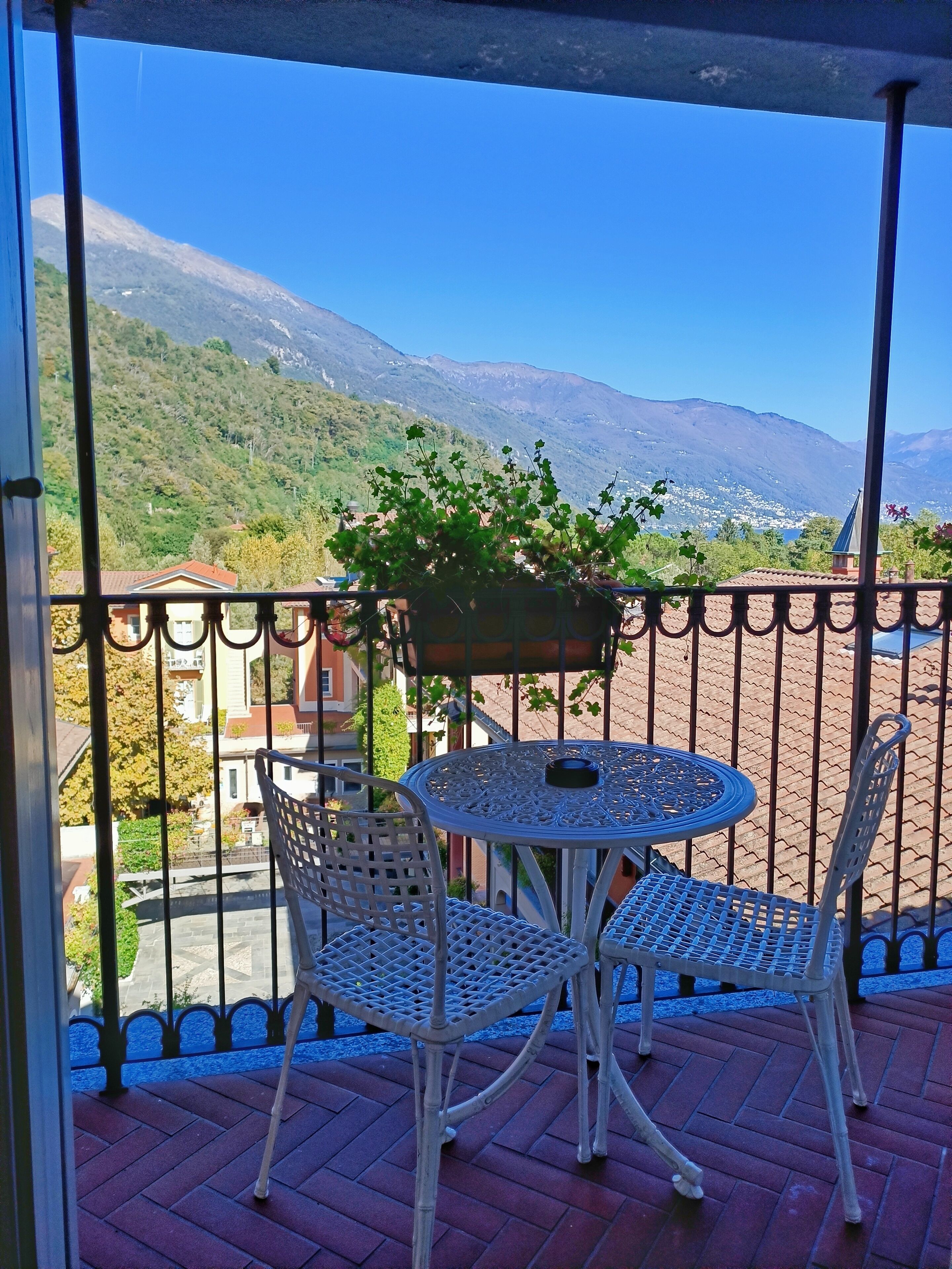 Een balkon met een tafel en stoelen, met uitzicht op een bergachtig landschap.