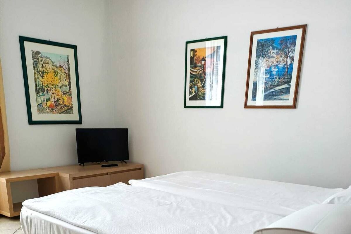 Een hotelkamer met een bed, nachtkastje met een lamp, een televisie en drie ingelijste foto's aan de muur.