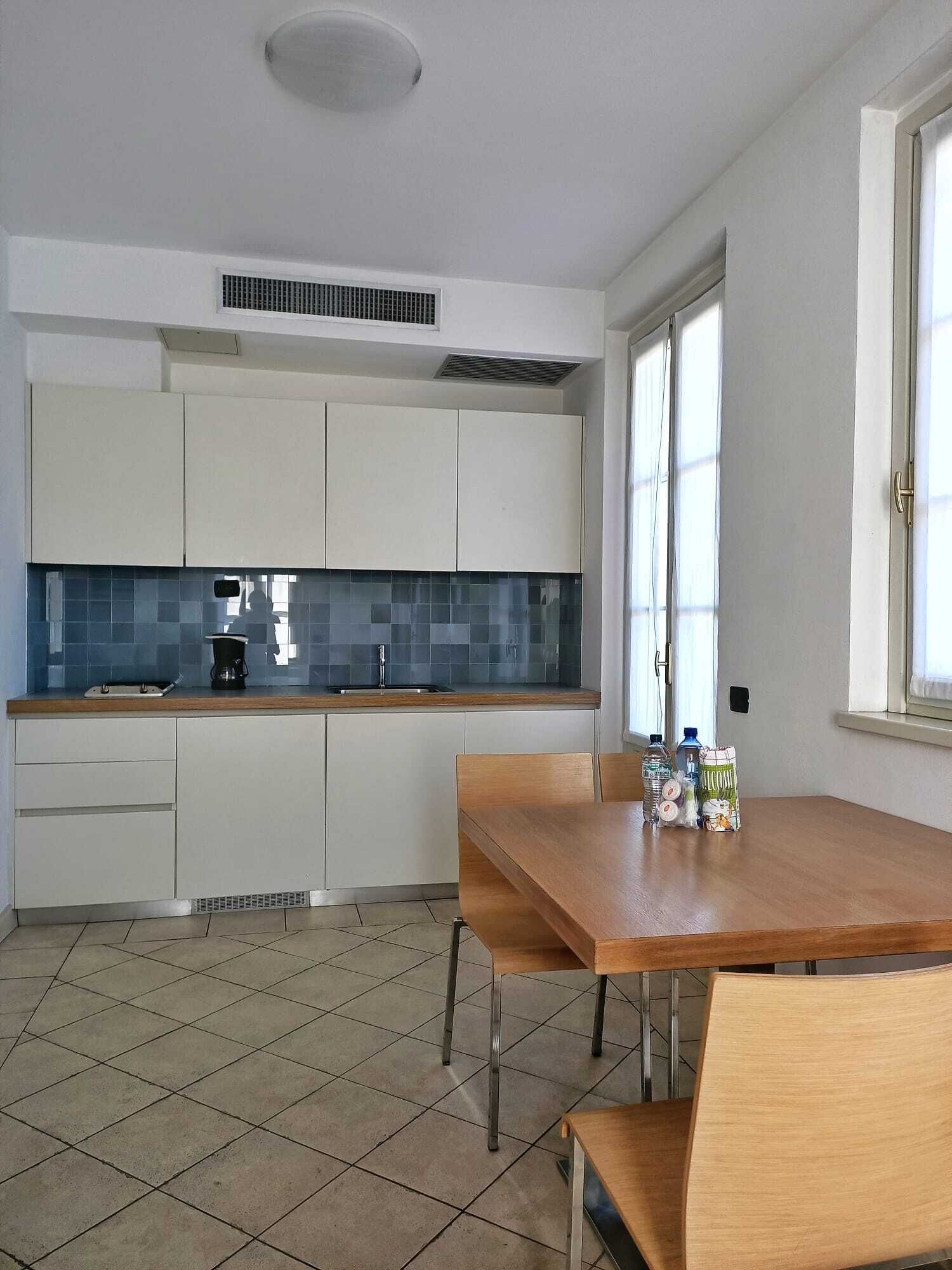 A modern kitchen with white cabinets, a blue backsplash, and a wooden dining table with chairs.