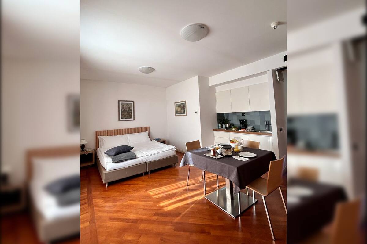 Een kleine kamer met een bed, een eettafel en een kitchenette.