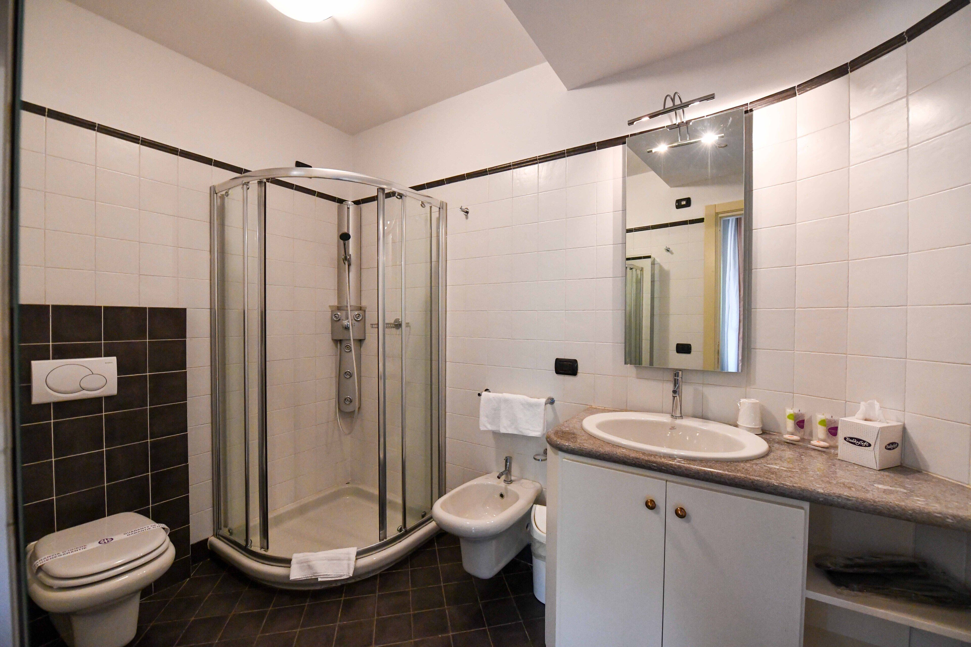 A modern bathroom with a glass-enclosed shower, a toilet, a bidet, and a sink with a vanity.