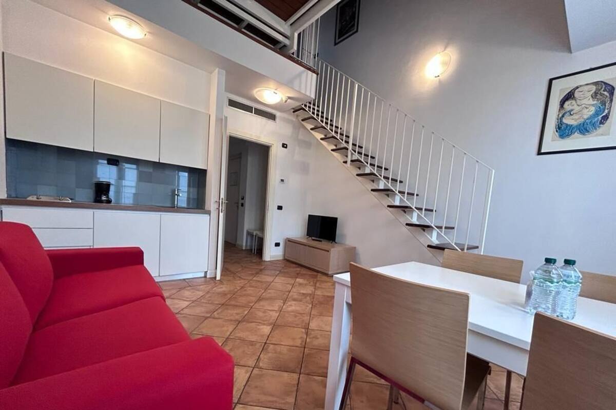 Een modern appartement met keuken, eethoek en een trap.