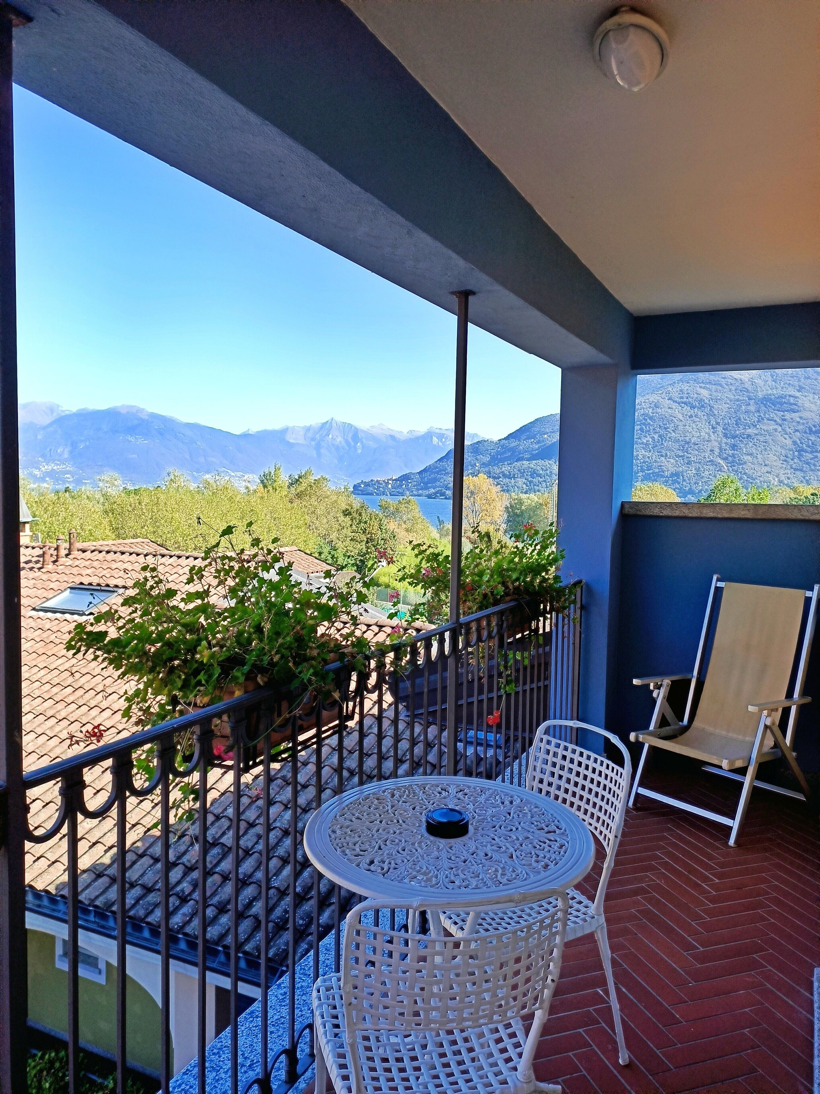 A balcony with a table and chairs, overlooking a mountainous landscape.