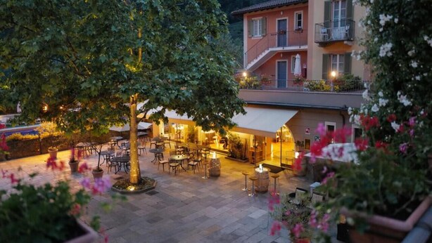 Un espace extérieur aménagé en terrasse, avec des tables et des chaises, entouré de plantes et de fleurs en pot.