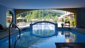 Une piscine intérieure offrant une vue sur un paysage montagneux et un pont.