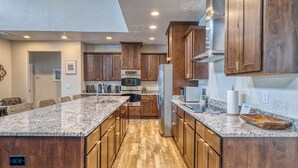 A spacious kitchen with wooden cabinets, granite countertops, and a central island. - Frio Ridge Retreat @ Frio Premier Rental Homes (Concan)