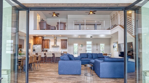 A spacious living area with a large sectional sofa, a dining table with chairs, and a kitchen in the background. - Frio Ridge Retreat @ Frio Premier Rental Homes (Concan)