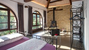 A bedroom with a bed, a fireplace, and large windows. - Cascina IL SOGNO  (Cossano Belbo)