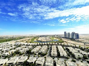 A residential area with apartment buildings, a river, and high-rise buildings in the background. - Tanin - Stunning Dubai Skyline View From this Sleek Studio (Dubai)