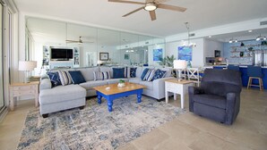 A modern living room with a sofa, armchairs, a coffee table, and a ceiling fan. - Gulf Front 3/3 Resort w/Pool & 3 King Suites! Chair/umbrella set-up included! (Navarre)